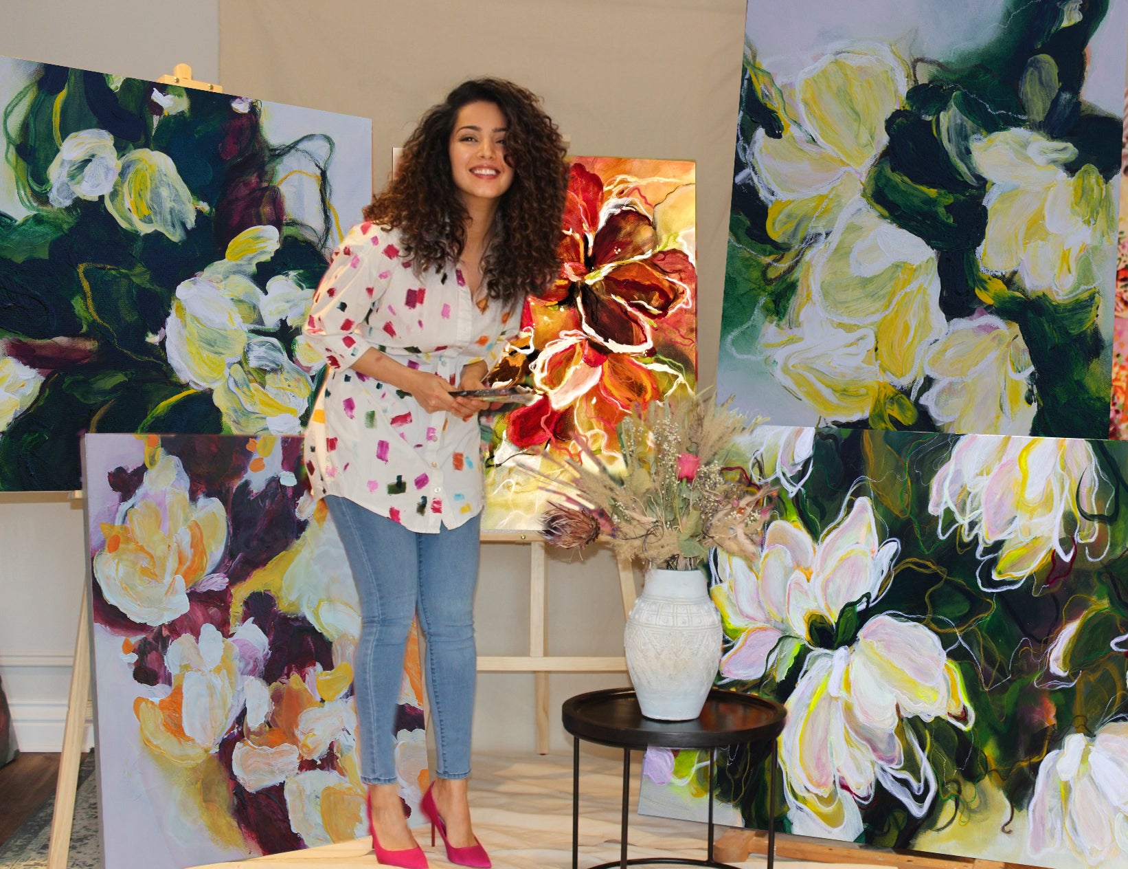 Mona, the artist behind the brand Mona Atiye in her studio surrounded by her original botanical floral abstract paintings