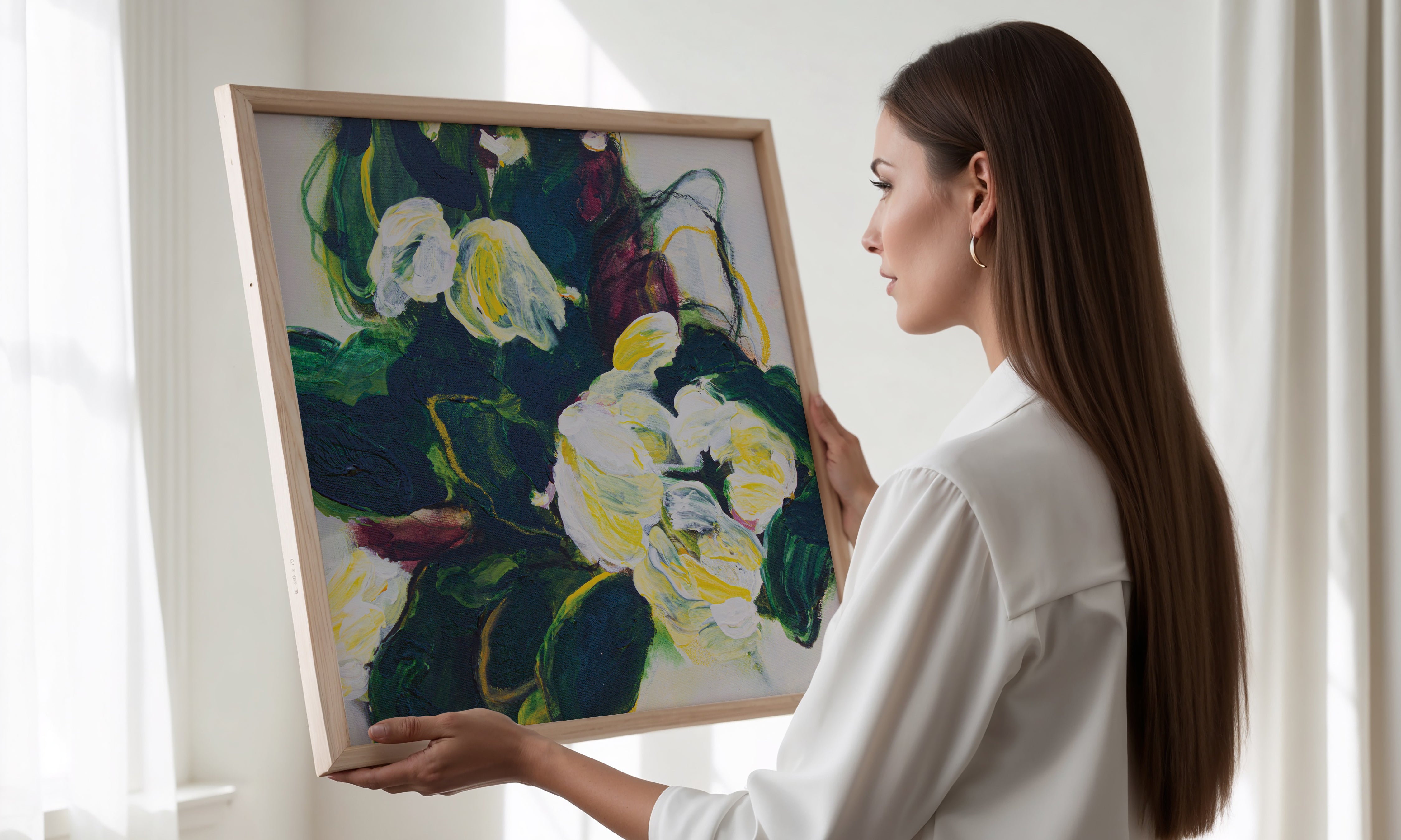 Woman and a white shirt holding a square framed print of Mona original artwork in the colours of green yellow burgundy and white