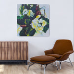 Modern living room with wooden sideboard, brown armchair, ottoman, and floral painting on white wall.