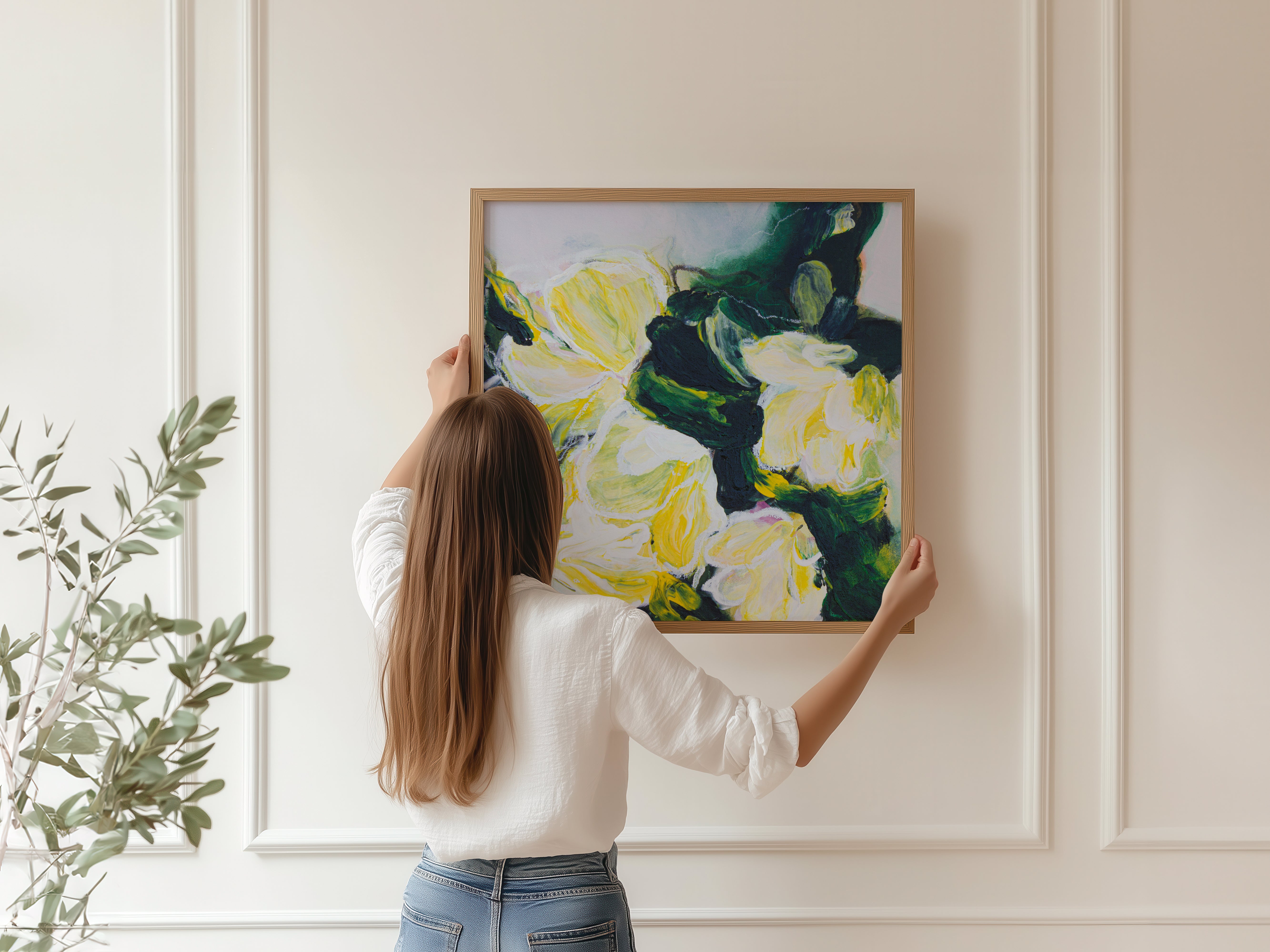 Person hanging a printed and framed abstract floral painting by Mona Atelier on a wall
