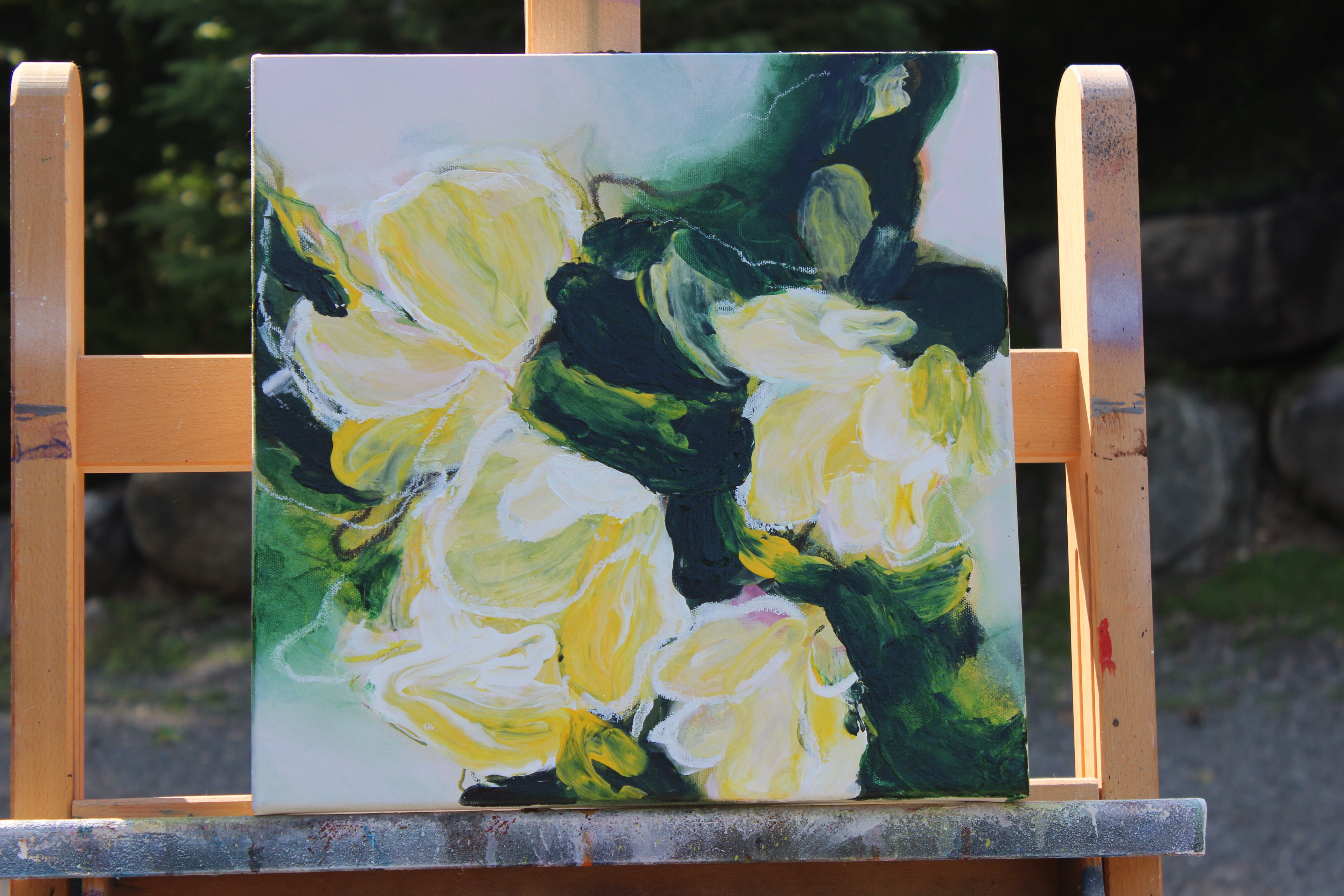 Painting of yellow flowers on a wooden easel outdoors